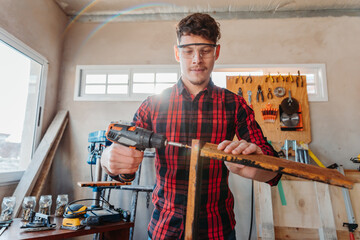 young caucasian carpenter screwing an electric screwdriver
