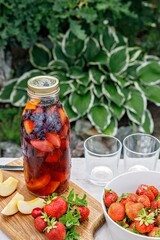 Refreshing homemade lemonade or sangria punch with citrus fruits and organic berries. Summer cocktail with ice and fruit juice in a glass bottle. Tasty drinks. Vertical shot