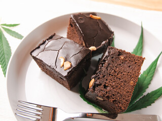 Homemade sweetmeat with marijuana or cannabis leaf on white plate. Alternative medicine concept..