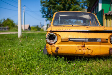 Old yellow wrecked car in vintage style. Abandoned rusty yellow car. Close-up of the headlights of...