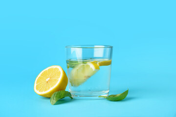 Glass of tasty lemonade with basil on color background