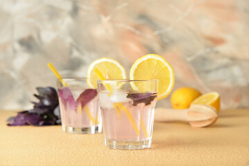 Glasses of tasty lemonade with basil on color background