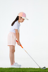 Portrait isolated studio shot of Asian little professional girl golfer in sport cloth uniform holding golf club driver in hands ready to drive and hit ball on green grass in front of white background