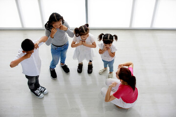 Top view shot of Asian female primary education school dancing teacher sit teach group of little...