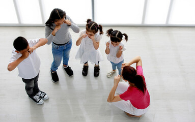 Top view shot of Asian female primary education school dancing teacher sit teach group of little...