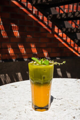 Refreshing iced matcha tonic with orange juice in a highball glass garnished with mint and thyme