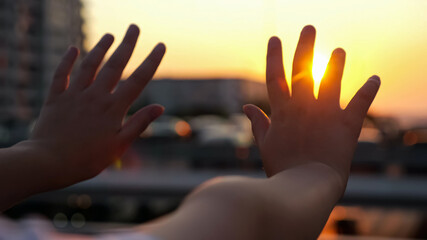 Schoolgirl hands at back sunset light. Girl arms over blurred metal handrails on city overpass...