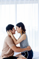 Delighted Asian couple hugging on bed