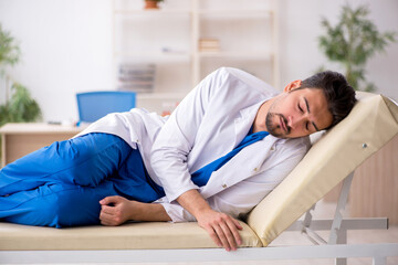 Obraz premium Tired young male doctor lying on the couch at the hospital