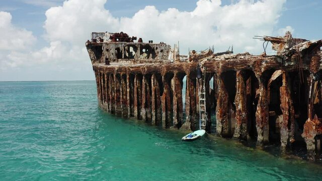 Tourist Climbs The SS Sapona Shipwreck On The Bahamas Ocean Near Bimini District. aerial