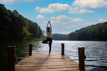 Young healthy woman practicing yoga on the bridge in the nature
