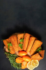 Fried fish cakes in the shape of triangles, breadcrumbs on wood. Dark background, top view. vertical orientation.Copy space.