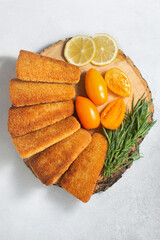 Fried fish cakes in the shape of triangles, breadcrumbs on wood. White background, top view.