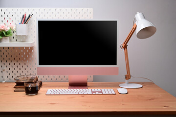 Modern workplace with computer, lamp and office supplies.