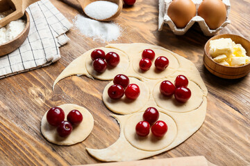 Fresh dough for cherry dumplings and ingredients on wooden background