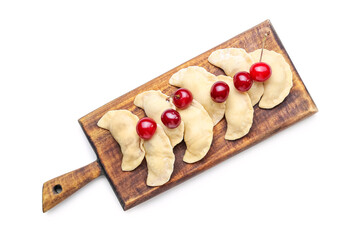 Wooden board with raw cherry dumplings on white background