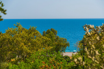 Fototapeta na wymiar ANTALYA, TURKEY: Trees and the Mediterranean Sea, Konyaalti beach in sunny summer in Antalya.