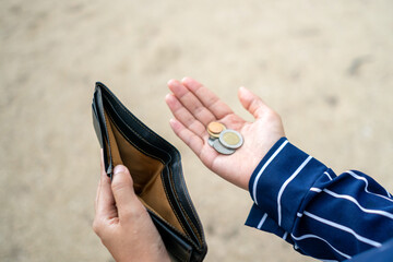 Woman holds an empty purse and coins in hand meaning money financial problem or bankrupt jobless,...