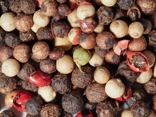 Close-up image of black pepper on a white background, the view above
