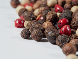 Close-up image of black pepper on a white background, the view above