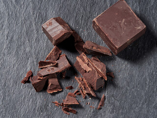 Broken pieces of chocolate and cocoa powder on a black background
