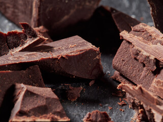 Broken pieces of chocolate and cocoa powder on a black background
