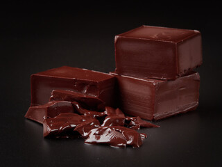 Broken pieces of chocolate and cocoa powder on a black background
