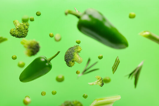 Flying Green Vegetables On Color Background