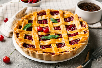 Plate with tasty cherry pie and cup of tea on grunge background, closeup