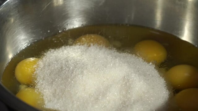 Cook pours sugar into a container with chicken eggs
