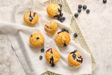Tray with tasty blueberry muffins on light background