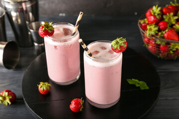 Glasses of strawberry Pina Colada cocktail and berries on dark wooden background