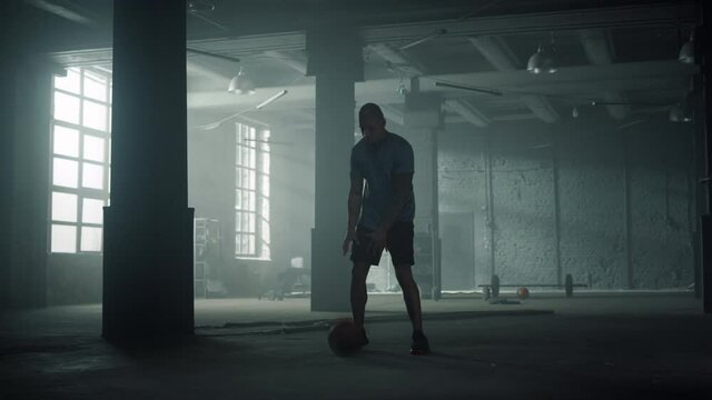 Basketball player training in sport club. Sporty man dribbling ball between legs