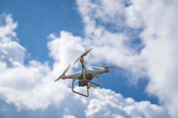 Naklejka na ściany i meble a white drone flies in the blue sky and shoots a video. 