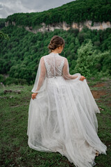 Fototapeta premium bride in a wedding dress posing in mountains. view from back. 