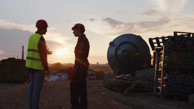 Two builders stand and discuss their new house project