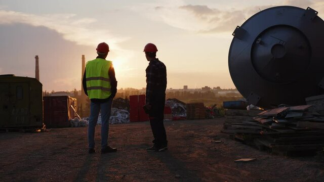 Two young men stand on the evening sunset