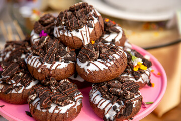 A view of a stack of chocolate donuts, featuring icing and cookies and cream crumbles.
