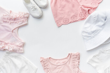 The layout of baby cotton clothes made from pink and white dresses, Panama hats, and sneakers with copy space