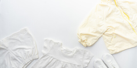 A set of white and yellow baby clothes on a white background with copy space. Panoramic photo