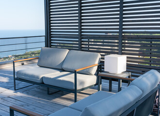 White sofas under a pergola on the roof of a house by the sea. Roof use concept in modern house