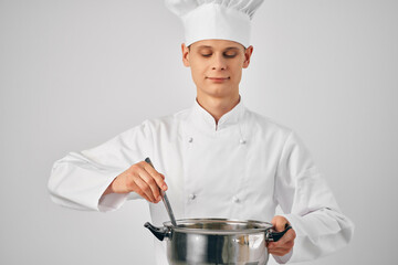 man in chef's clothes with a saucepan in his hands preparing food light background