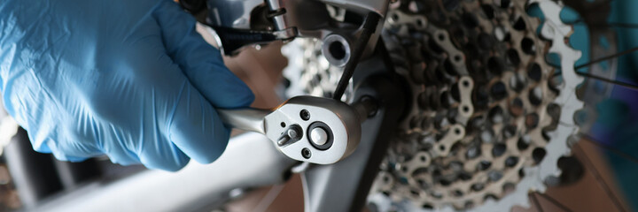 Foreman repairman in rubber gloves repairing bicycle closeup