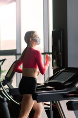 Fototapeta premium Woman wearing face mask exercise workout in gym during corona virus pandermic.