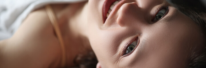 Young smiling woman lying in bed and looking up