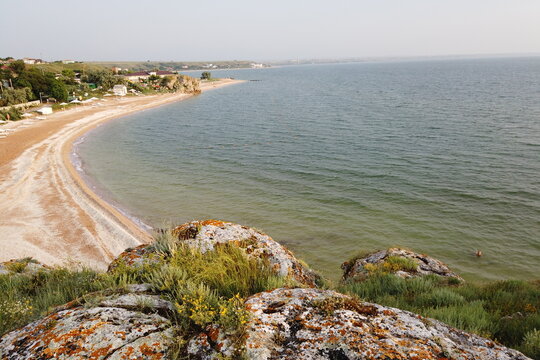 natural landscape at sunset, rocky rocks covered with moss and lichen in the foreground, a deserted beach in the distance