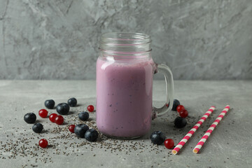 Glass jar of smoothie, ingredients and straws on gray textured table