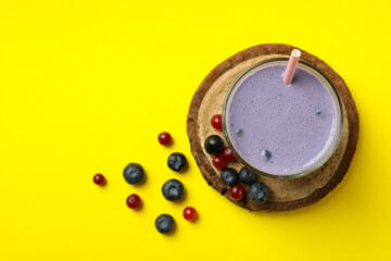 Fresh blueberry smoothie and ingredients on yellow background