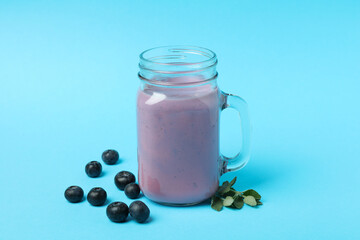 Fresh blueberry smoothie and ingredients on blue background