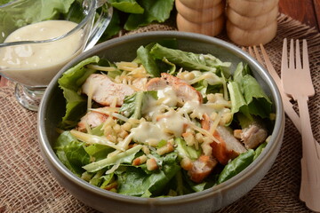 Caesar Salad with grilled chicken, Cheese and Croutons with lettuce, on plate.  Grilled chicken breasts and fresh vegetables in plate.
